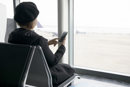 Woman on her smart phone waiting at the airport .の写真素材