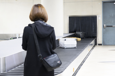 Wheeled suitcase on a luggage belt at the airport terminal.の写真素材