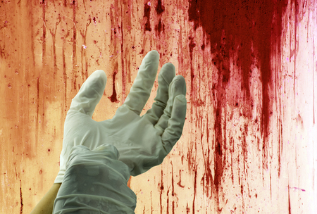 Concept of murder bloody on wall and human hand with rubber gloves.の写真素材
