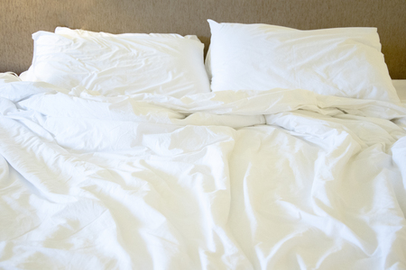 Messy white bed and pillow, in the morningの写真素材