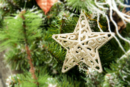 Christmas star on tree. Closeup on Christmas tree decoration over festive themeの写真素材