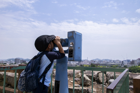 Boy try to looks in binocular on Himeji castle.のeditorial素材