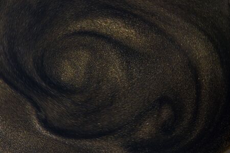 Golden glitter dust on dark background.の写真素材