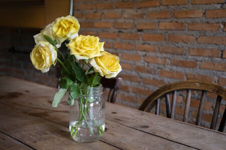 Yellow Roses in a vase on a table in a restaurantの写真素材