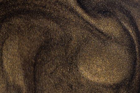 Golden glitter dust on dark background.の写真素材