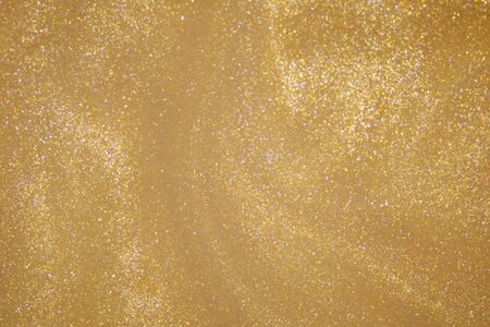 Golden glitter dust on dark background.の写真素材