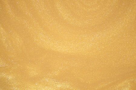 Golden glitter dust on dark background.の写真素材