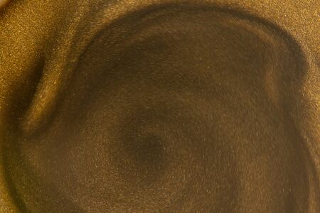 Golden glitter dust on dark background.の写真素材