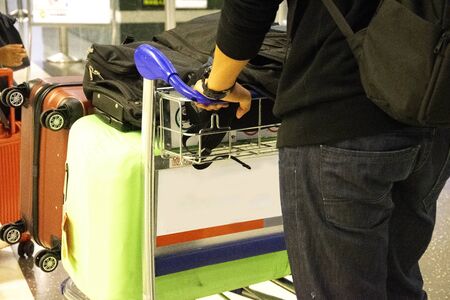 man holding cart of suitcase or baggage with airport luggage trolley in the international airportの写真素材