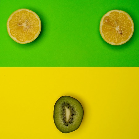Smiley from the kiwi and lemon on a colored background. Fresh kiwis and lemon fruit, interesting fruit compositionの写真素材