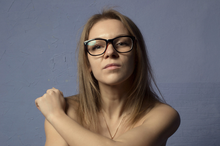 Closeup portrait of  blonde woman with glasses, isolated on blue background.の写真素材
