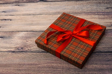 Small gift box with red ribbon on wooden tableの写真素材