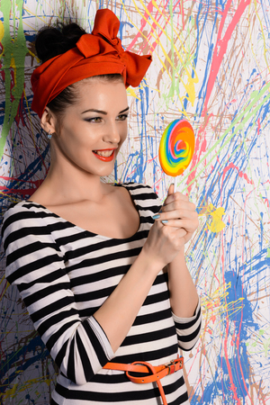 portrait of beautiful girl with big lollipop at wall with different color splashの写真素材