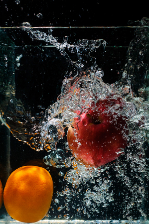 orange dropped in fish tank filled with water.の写真素材