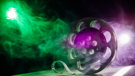 Movie reel of film in retro in the smoke of green and purple on a dark backgroundの写真素材