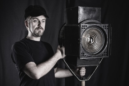 Man wearing a cap stands near a stage spotlight on black background. black and whiteの写真素材