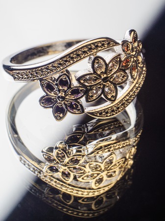 Silver Ring decorated with precious stones sapphire, cubic zirconia, ruby in the shape of flowers on a mirror surfaceの写真素材