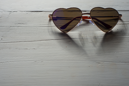 Heart shaped rainbow sunglasses on wood texture.の写真素材
