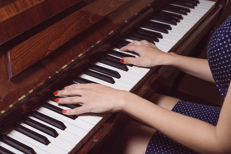 Beautiful female hands on the keys of an old piano. close-up