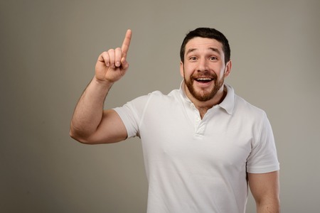 Young man has idea, pointing with finger up isolated on gray background. Smart guy solved a problem....