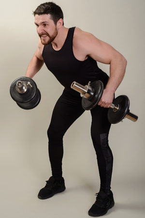 A young athlete performs an exercise with dumbbells on the development of the muscles of the shoulders.の写真素材