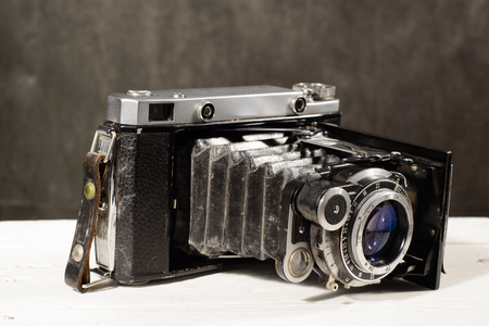 Old vintage camera on white wooden table black background.の写真素材