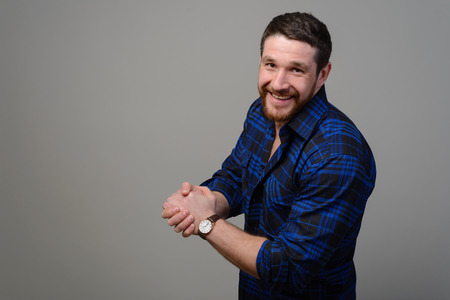 Happy handsome young man standing with arms crossed on gray backgroundの写真素材