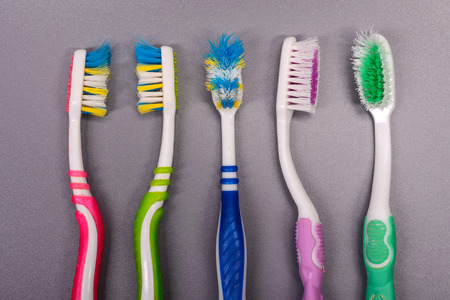 Five Old colorful toothbrushes on gray background.の写真素材