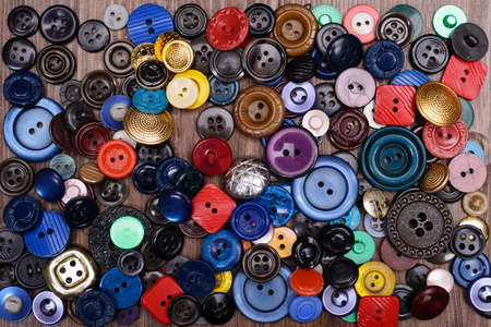old multi-colored buttons scattered on a wooden background.の写真素材