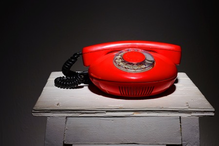 Old red vintage phone on a white chair stool.の写真素材