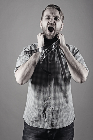 an angry man screams with a film on his neck.の写真素材