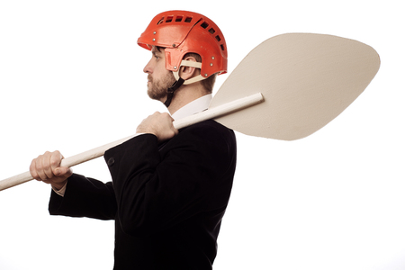 balanced businessman in a red helmet and with an oar in his hands on white backgroundの写真素材
