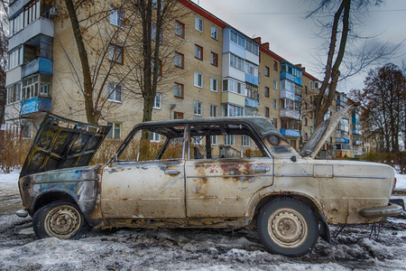 burnt out car near an apartment buildingの写真素材