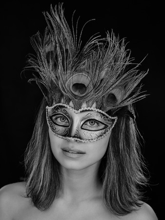Black and white close-up portrait of a beautiful green-eyed woman in a Venetian carnival mask on a dark background. ring flashの写真素材