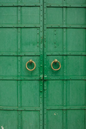 large antique wooden green doors with ring-shaped handles.の写真素材