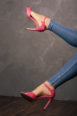 Women's legs in pink sandals with high heels in the interior.の写真素材