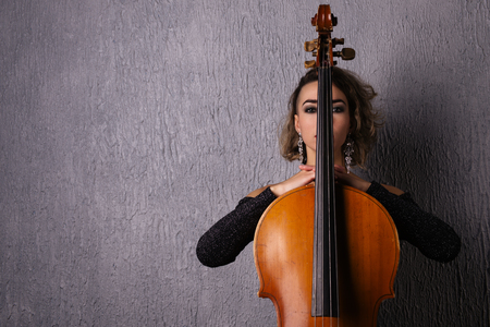 Portrait of a young sad woman. Part of the face is covered by the neck of the cello.の写真素材