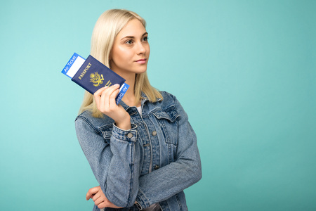 Dreamy girl in a denim jacket holds a passport with airline tickets - imageの写真素材