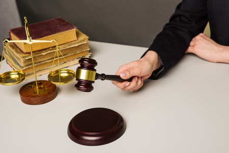 Woman Hand about to bang gavel on sounding block in the court room - image