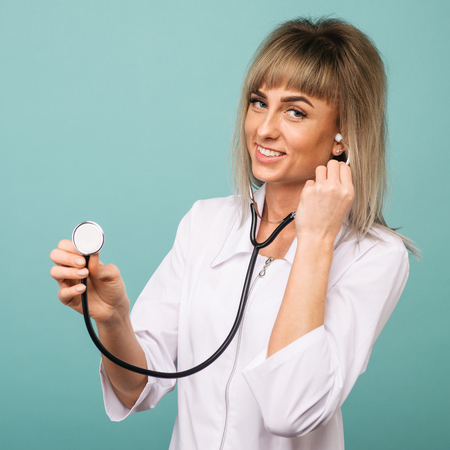Young female doctor with stethoscope on foreground. Cut out of face isolated on blue backgroundの写真素材