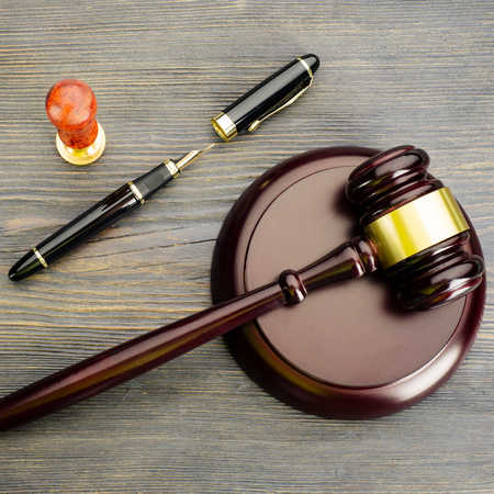 Judge's gavel, fountain pen and a stamp on an old wooden table - Imageの写真素材