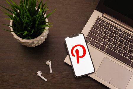 Tula, Russia - May 24,2019: Apple iPhone X and Airpods on desk with Pinterest application on the screen. Pinterest is an online pinboard that allows people to pin their interesting things.のeditorial素材