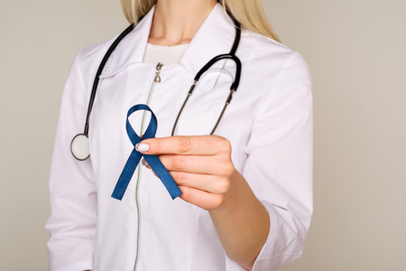 Doctor hands holding blue ribbon, diabetes and Colorectal Cancer Awareness - Imageの写真素材