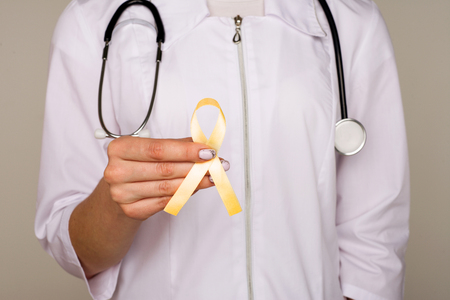 Yellow ribbon symbolic color for Sarcoma Bone cancer, Bladder health, Liver disease, Spina Bifida Awareness Month and suicide prevention in doctor's hand - Imageの写真素材