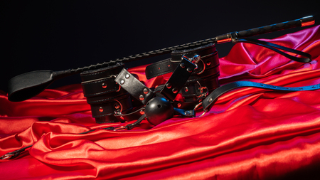 Adult sex games. Kinky lifestyle. Spank, Bondage and gag ball on the red linen. Bdsm outfit Concept - Imageの写真素材