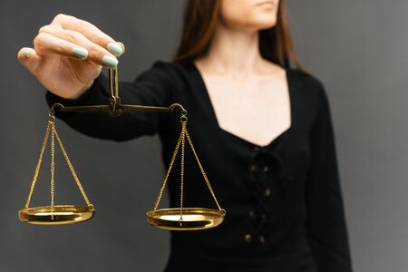 Serious woman holding the justice scale on dark background - imageの写真素材