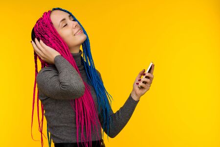 Happy cheerful woman with senegalese braids and freckles wearing wireless headphones listening to...