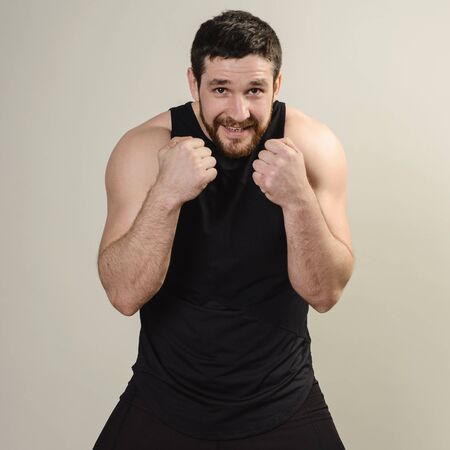 The fighter is in a frontal protective pose against a gray background.