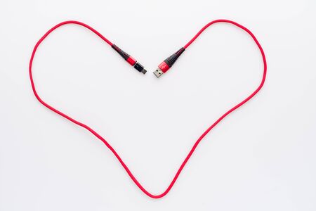 Charging and connection red cable USB to micro with type c adapter folded in the shape of a heartの写真素材