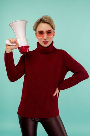 Angry woman in pink sunglasses with a megaphone on blue background - Imageの写真素材